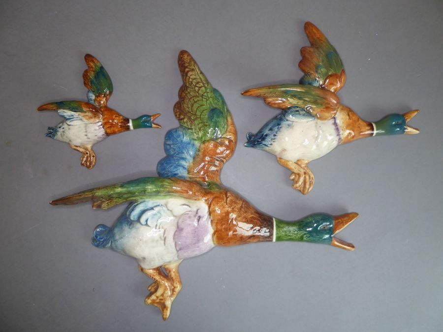 A set of three hand-decorated pottery wall-hanging flying ducks (the largest 35cm)