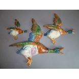 A set of three hand-decorated pottery wall-hanging flying ducks (the largest 35cm)