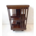 An early 20th century revolving oak bookcase on stand with castors (46cm square x 83cm high)