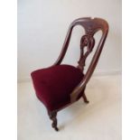 A late 19th century mahogany-framed low nursing-style chair having ornately carved pierced splat,