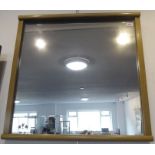 A modern light oak-framed wall-hanging looking glass (frame size 63cm square)