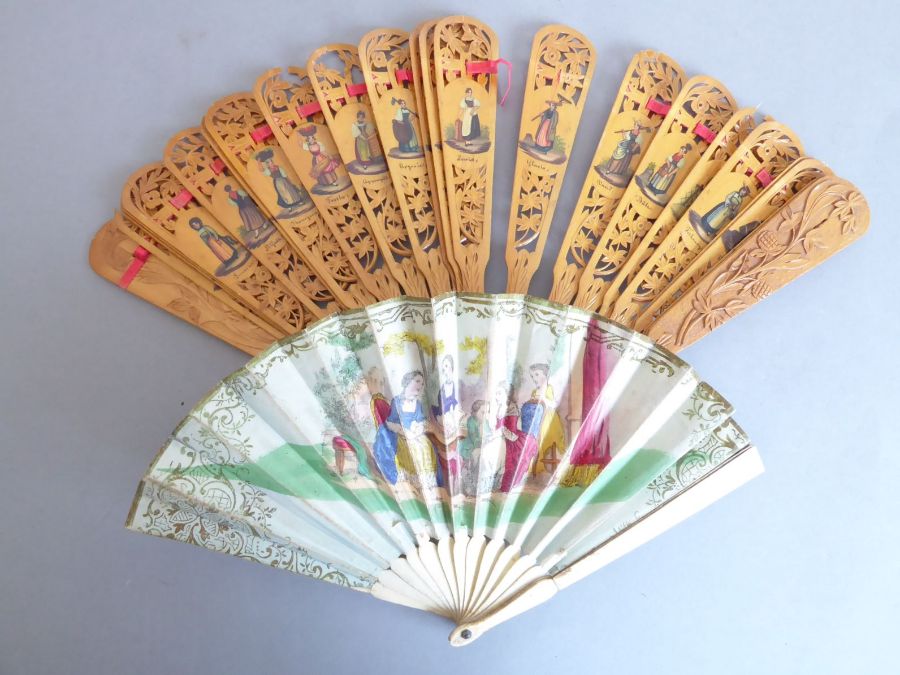 An early 20th century pierced wooden fan decorated with various Swiss costume, together with a