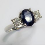 A sapphire and diamond three stone ring; the central oval mixed-cut sapphire set to either side with