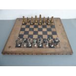 A leather-embossed chessboard complete with two full sets of heavy cast-metal chess pieces (the