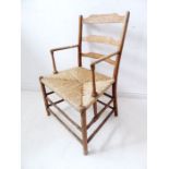 An early 20th century ash and rush seated ladderback open armchair in William Morris Arts and Crafts