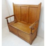 An early 19th century pine settle; the three panelled back above straight horizontal arms and a
