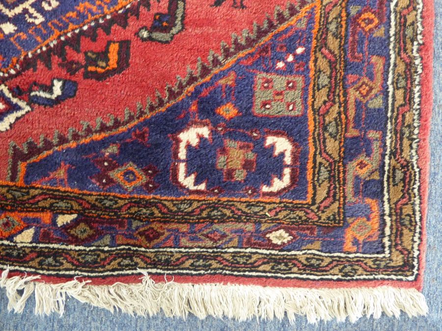 A red ground Hamadan hand knotted rug with three rug with three central lozenges against a red - Image 3 of 5