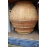 A very large patinated terracotta amphora / olive jar of ovoid shape; outset lip above two applied