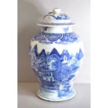 A baluster jar and cover painted in underglaze blue with buildings under towering peaks, the