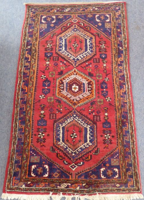 A red ground Hamadan hand knotted rug with three rug with three central lozenges against a red