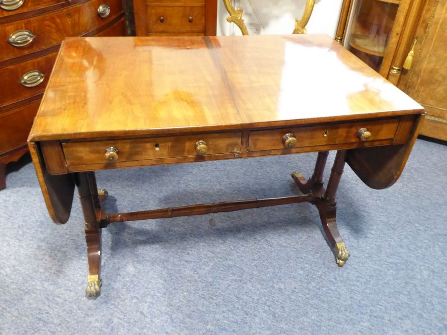 An early 19th century Regency period sofa table; the drop leaves flanking two half-width drawers,