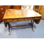 An early 19th century Regency period sofa table; the drop leaves flanking two half-width drawers,