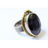 A bespoke silver ring; the textured ring with large applied central dark-blue hand-cut stone with