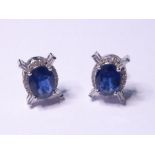 A pair of 18-carat white-gold earrings set with a large central sapphire bordered by diamonds