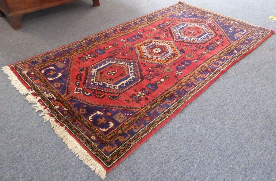 A red ground Hamadan hand knotted rug with three rug with three central lozenges against a red - Image 2 of 5