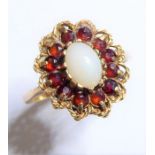 A 9-carat yellow-gold dress ring centrally set with a cabochon opal surrounded by twelve garnets,