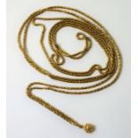 A yellow gold fancy link long chain necklace suspending a small, hollow yellow gold charm (