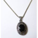 An oval silver pendant centrally set with a black polished cabochon hardstone, upon a silver
