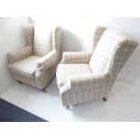 A pair of chequer upholstered armchairs; each raised on turned wooden legs terminating in brass