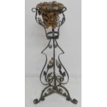 A decorative green-painted wrought-iron plant stand decorated with flowers and leaves and then upper