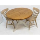 A modern circular pine kitchen-style table with cream painted tripod base in shabby chic style,