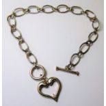 A silver bracelet with a T-bar to one end and the other terminal modelled as a heart