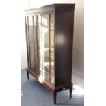 A two-door glazed mahogany cabinet with shelves raised upon a stand with square tapering legs and