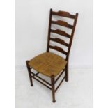 An Arts and Crafts style stained beech ladderback chair having rush-woven seat and in the style of