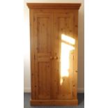 A modern pine two-door wardrobe of slim proportions; removable cornice over two panelled doors