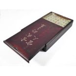 An early/mid 20th century stained wood cased mahjong set, the tiles of bone and bamboo