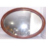 An early 20th century oval mahogany wall-hanging looking glass having bevelled plate (85.5cm x