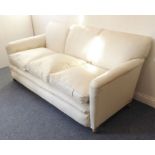 A large and comfortable early 20th century cream vinyl upholstered three-seater sofa on casters (