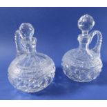 A pair of 19th century cut-glass flasks with arched faceted handles (one stopper replaced)
