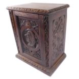 A late 19th / early 20th century oak table cabinet; the single panelled door centrally decorated