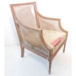 A stripped wood and rattan-caned bergère-style chair raised on turned, tapering fluted front legs