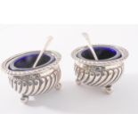 A pair of silver salt cellars with blue-glass liners (Birmingham 1898) and two later spoons (
