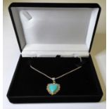 A silver heart-shaped pendant set with a polished cabochon-style turquoise stone, suspended from a