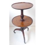 A George III period two-tier mahogany wine table on tripod base with brass castors (the top shelf