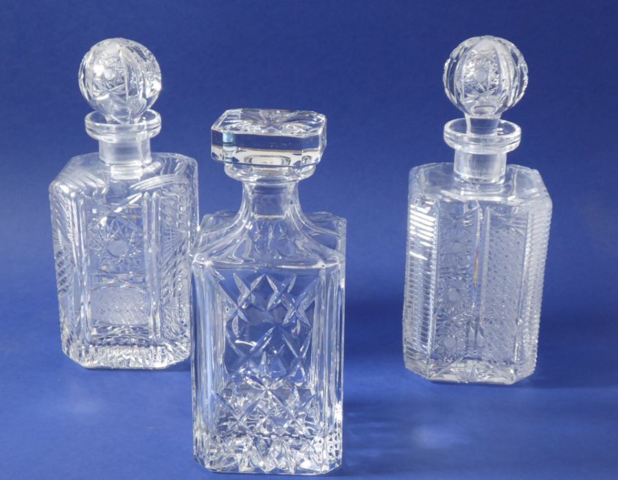 Three fine quality hand-cut spirit decanters of square form and with canted corners