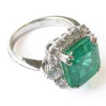 An 18-carat white-gold cluster ring set with a 5.1 carat emerald and 1.2 carats diamonds, size