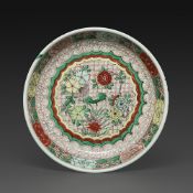 PLAT en porcelaine et émaux wucai, à décor en médaillon central de pivoines, chrysanthèmes