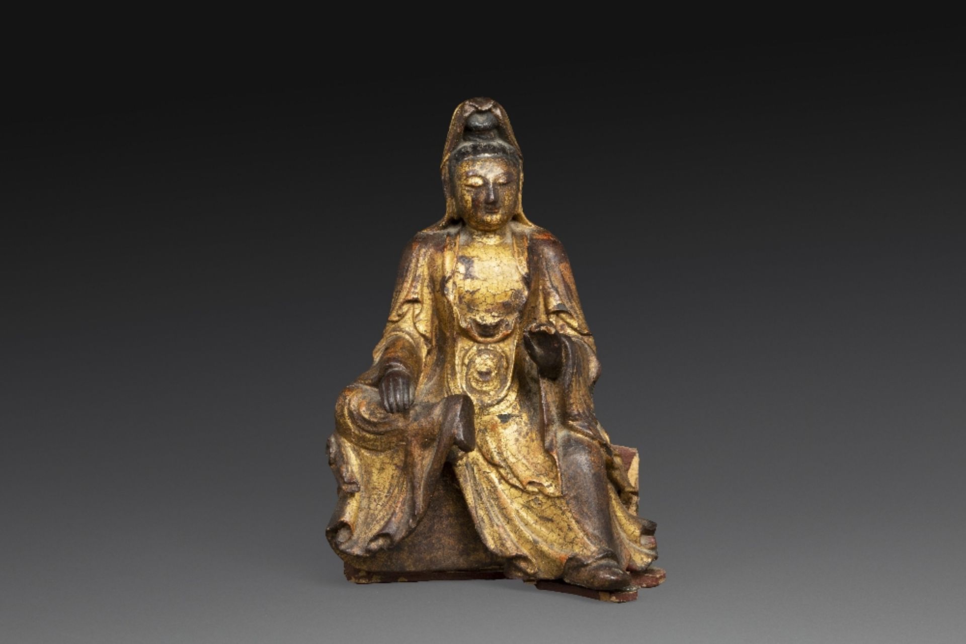 STATUETTE en bois laqué et doré, représentant la déesse Guanyin assise sur un socle. (Lacunes de