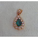 EMERALD AND DIAMOND PENDANT WITH PEAR SHAPED EMERALD IN A CLAW SETTING IN A SURROUND OF ROUND