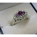 18CT GOLD RUBY & DIAMOND SET RING, THE 3 GRADUATED RUBIES IN A SURROUND OF APPROX 0.