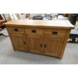 OAK SIDE BOARD OF 3 DRAWERS OVER 3 PANEL DOORS ON SQUARE SUPPORTS.