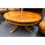 CROSSBANDED OAK CIRCULAR PEDESTAL COFFEE TABLE WITH 4 SPREADING SUPPORTS WITH BRASS FEET.