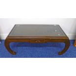 EASTERN HARDWOOD COFFEE TABLE WITH CARVED ORIENTAL DECORATION AND GLASS INSERT ON SHAPED SUPPORTS.