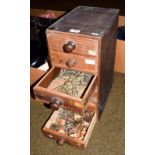 A six drawer wooden cabinet containing a clock makers parts, including clock keys, clock hands,
