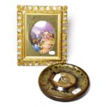 A Victorian circular brass inkstand dish, with pen and a Continental porcelain plaque depicting