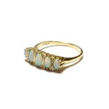 A 9 carat gold opal ring, the five graduated oval opals with eight cut diamond accents, to a plain